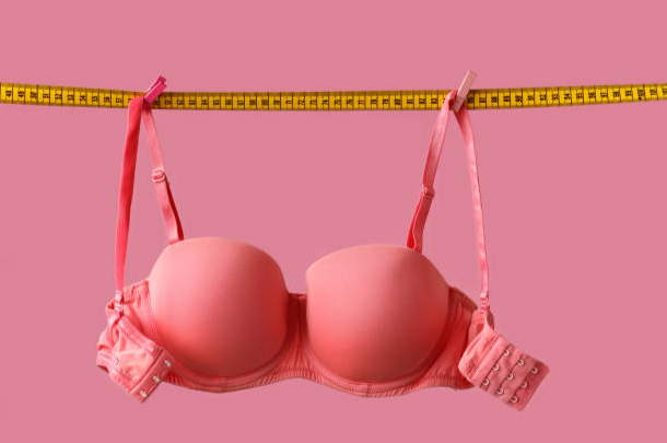A bra with measuring tape holding it up 